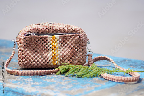 Crochet crossbody bag with yellow accent on blue wooden surface