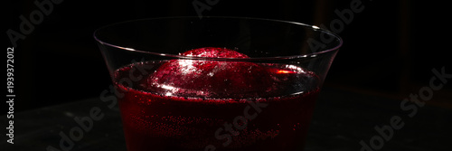 Fotografija A crimson cocktail glimmers in shadowy light, encapsulating the mystique of Luna