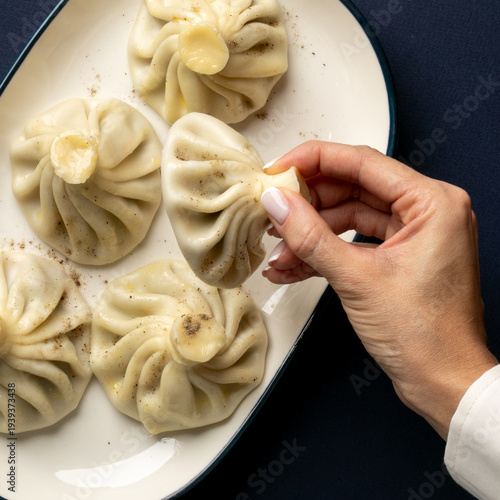 Delicate khinkali dumplings cradled by a hand imply Georgian feasts and Lunar New Year, evoking culinary artistry
