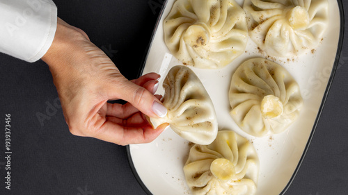 Tableau sur toile Delicate hands serve steaming khinkali, Georgian dumplings, serenading World Dum