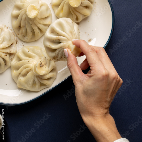 Konstfotografi A hand tenderly pinches a Georgian dumpling, echoing the festive spirit of Supra