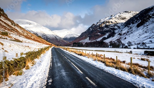 Winter landscape of a valley with road, snow covered hills, and sky with clouds creates a scenic, serene view