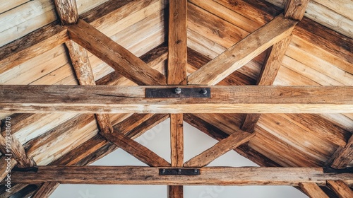 Intricate rustic timber beams forming the structural element of a wooden roof and ceiling, showcasing aged wood texture and joinery details.