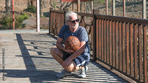 Portrait of a confident senior man holding a basketball as he heads out onto an outdoor court for a workout. Concepts about elderly lifestyle and quality of life