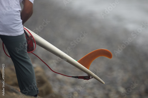 classic longboard fin and leash resting on a surfboard at the shoreline, capturing an essential piece of surfing equipment before entering the Pacific waves. The image reflects the spirit of an active