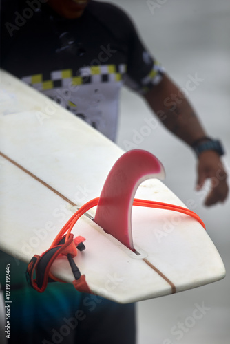 Photography classic longboard fin and leash resting on a surfboard at the shoreline, capturing an essential piece of surfing equipment before entering the Pacific waves