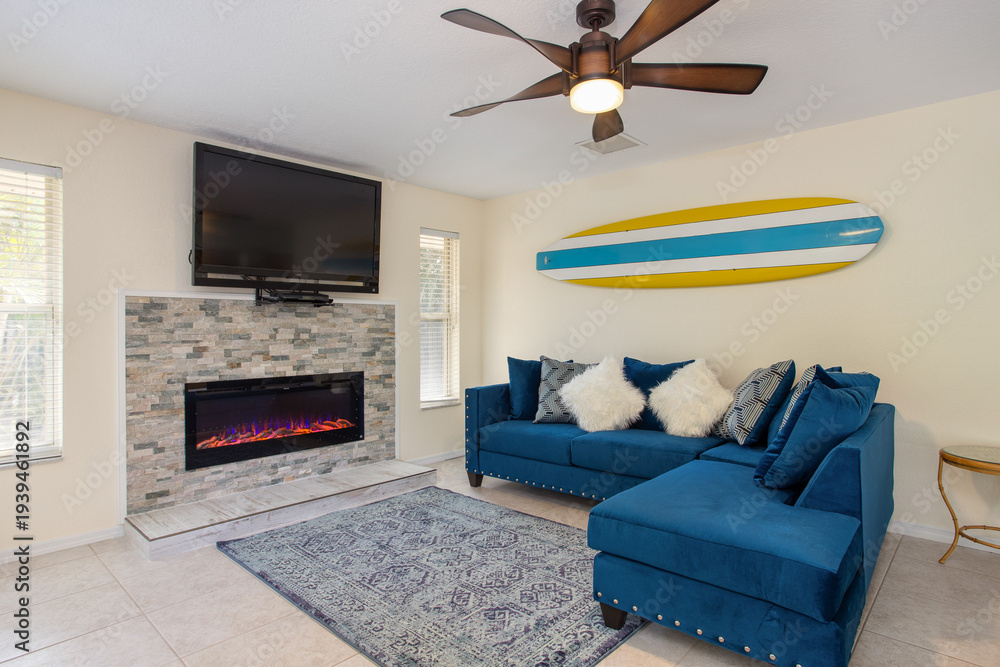 Fototapeta premium Bright family room in a Florida vacation home with fireplace feature and surf decor