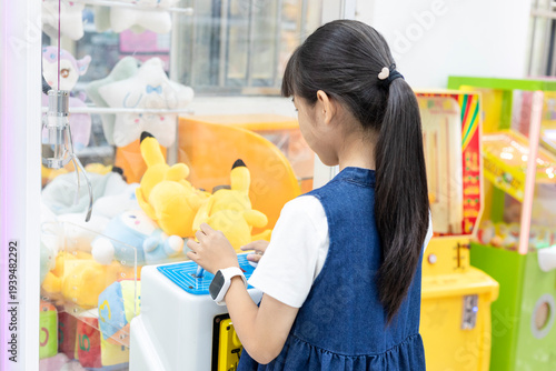Fotografia A young Chinese girl wearing a children's smartwatch plays at a claw machine