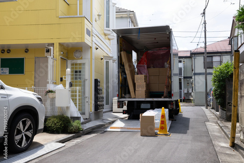 引越し作業中の引越し業者、住宅街での配送作業中のトラック