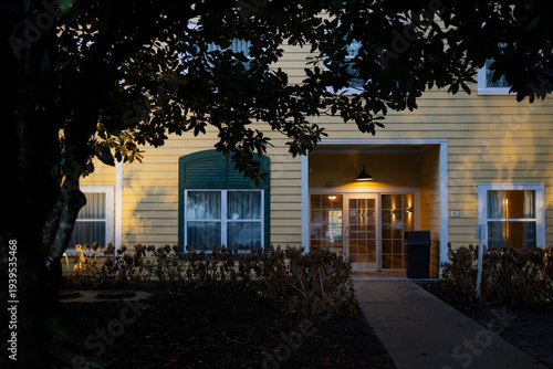 Εκτύπωση καμβά Warm evening entrance of a yellow lodging building in Florida framed by dark tre