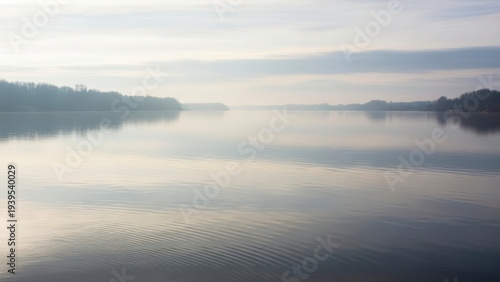 Foggy landscape with water and hills.