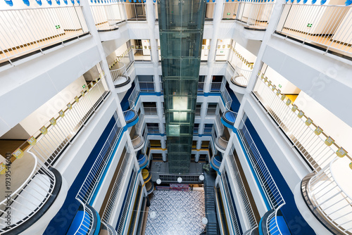 Photography Modern hotel atrium with glass elevator and multi-level balconies featuring blue