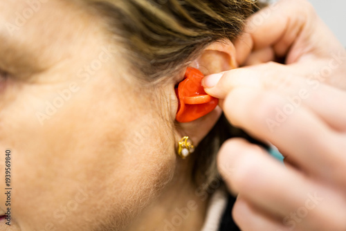 Obraz na płótnie Close-up photograph of an ENT specialist inserting a custom-made silicone earplug into an elderly woman