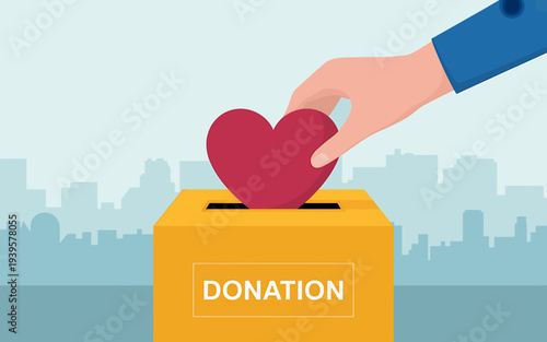 Hand putting heart into donation box for charity on cityscape background