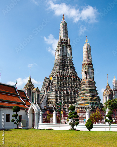 The central prang and gardens in the grounds of Wat Arun, Bangkok under a predominantly blue sky