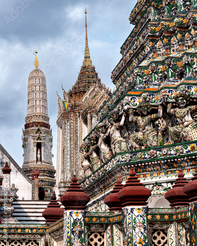 Ceramic tile detail on the central prang in Wat Arun, Bangkok under a cloudy sky