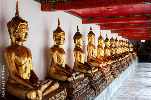 Gold sitting buddhas line a wall at Wat Pho in Bangkok, Thailand