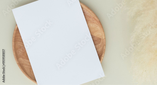 Blank white card on wooden plate with beige background