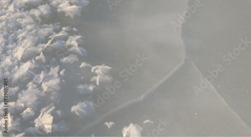 Frozen lake surface with delicate ice crystals and smooth gray ice