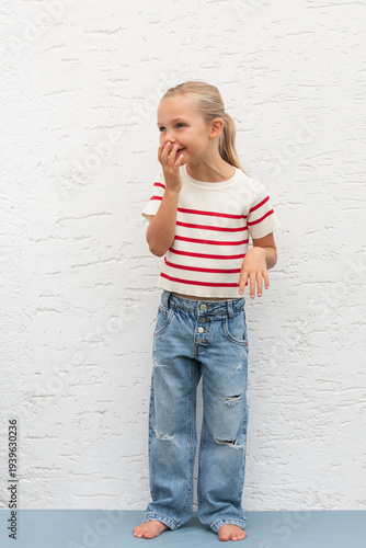 young girl standing with kind of covered laughing holding one hand at her mouth, facial funny expression of what is this