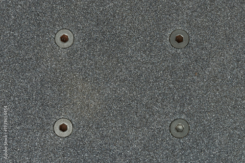 Close view of a skateboard deck with grip tape and screws
