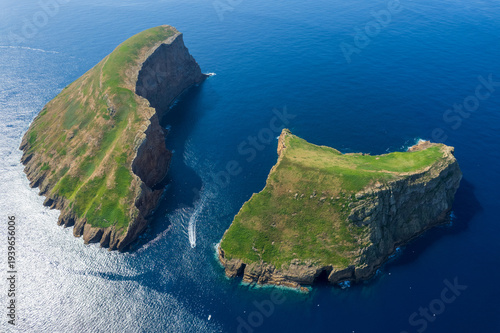 Aerial view of Terceira islans in Azores, Portugal. Volcanic landscape.  Drone shot of rock formations on the Atlantic coast and  cabras islet. Green fields in rural environment.