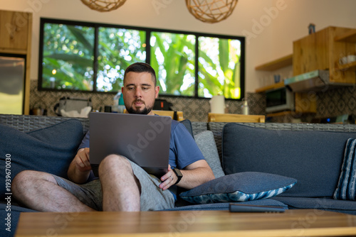 Man working remotely on laptop at tropical home