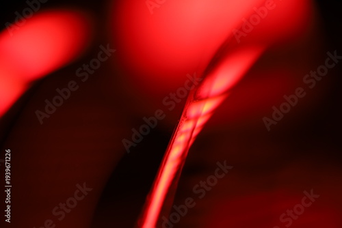 Abstract macro photo of a glowing red liquid line with soft blur and smooth gradients. Dark red and black background with dramatic lighting creates a mysterious, futuristic, and atmospheric texture. 