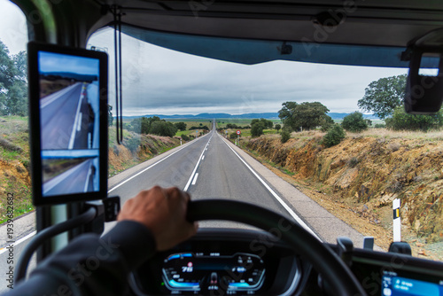 View from inside a truck of a straight road that disappears into the horizon.