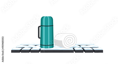 A teal thermos flask and a rolled white towel sit together on a snow-covered surface of dark grey rectangular bricks.