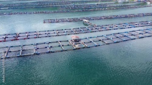 Aquaculture fish farm floating cage grid in ocean for seafood production and marine farming industry aerial
