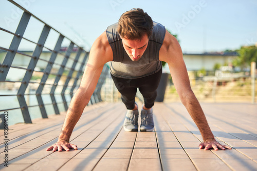 Young man performing push-ups on bridge pavement