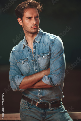 Confident man in denim shirt posing with crossed arms