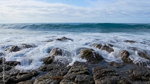 Crashing Waves on Rocky Shoreline with Sky and Clouds in the Background