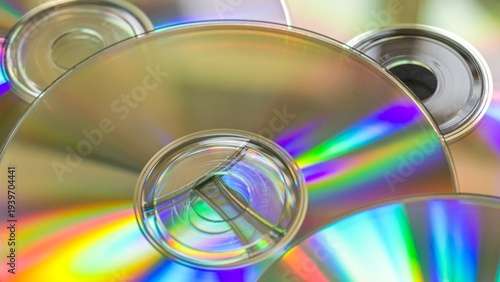 Wide 16:9 close-up of iridescent compact discs with shallow depth of field