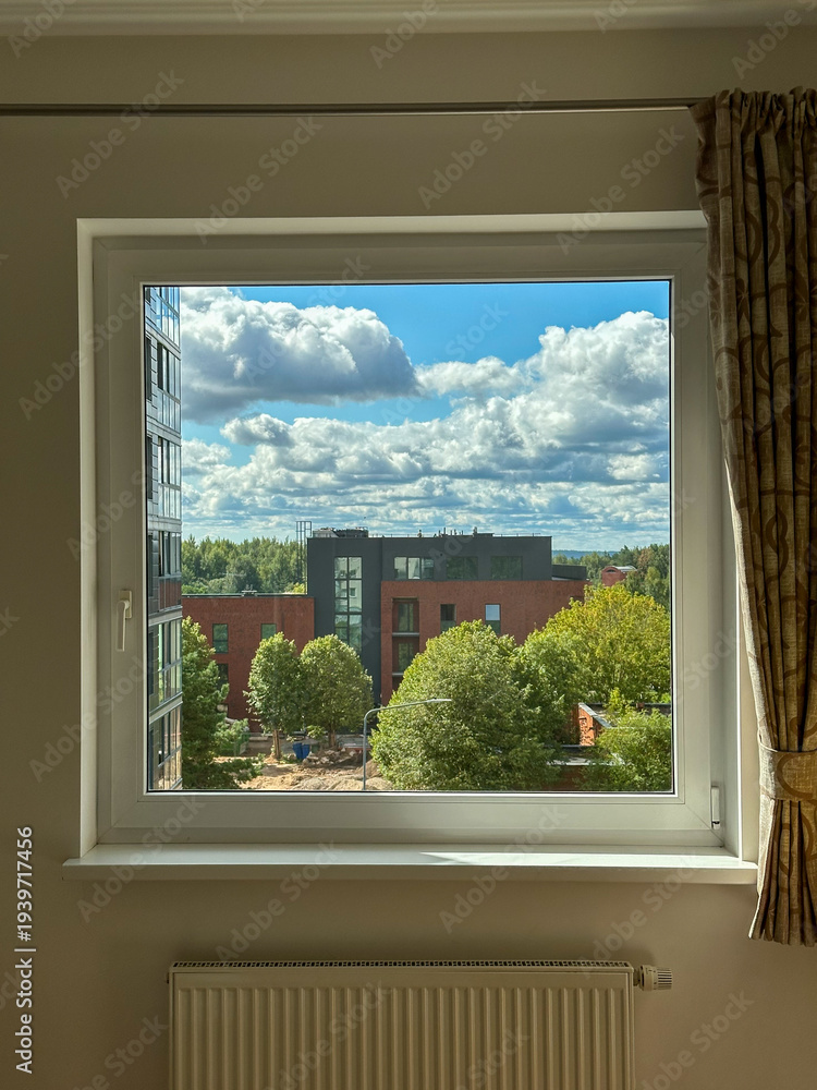 Fototapeta premium View of summer sky and residential buildings through apartment window