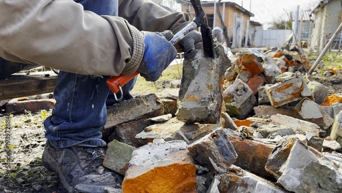 Obraz na plátne Male hands in protective gloves uses hammer to remove old cement from used bricks during renovation work