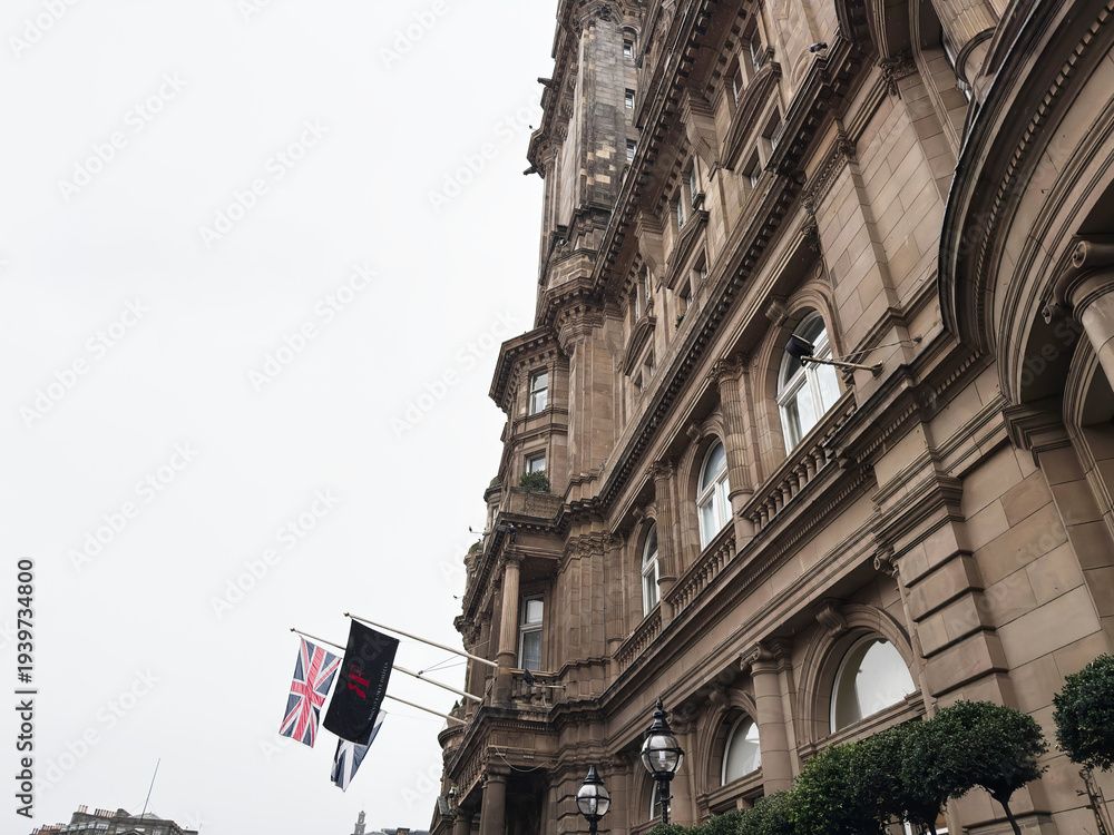Naklejka premium Historic sandstone building facade with Rocco Forte Hotels flags and ornate architecture in Edinburgh, Scotland, UK