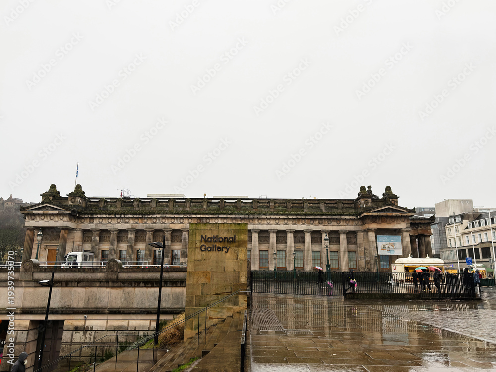 Naklejka premium National Gallery building in Edinburgh, Scotland, UK on a rainy day with neoclassical facade and wet reflective city square