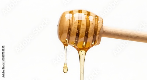 Honey dripping from a wooden honey dipper on a white background
