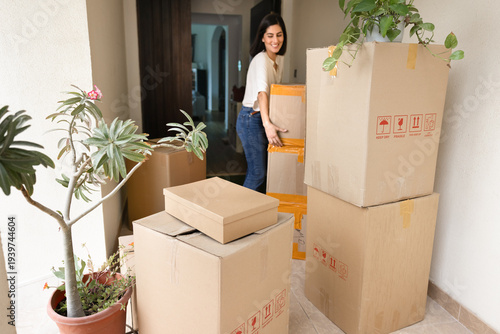 Slika na platnu Positive new tenant or homeowner woman moving into new house, carrying stacked b