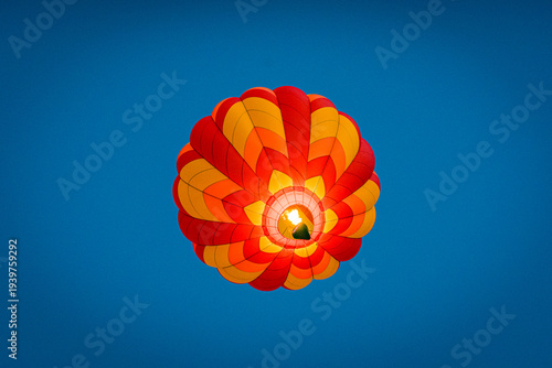 Colorful hot air balloon floats in clear sky during sunny day, capturing attention from below with its vibrant design