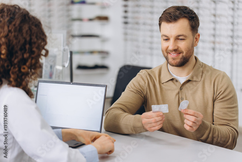 Photos Young man discussing soft contact lenses with optometrist, receiving advice for