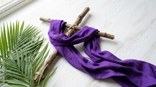 Purple Semana Santa fabric ribbon tied on wooden cross with palm leaves on white background