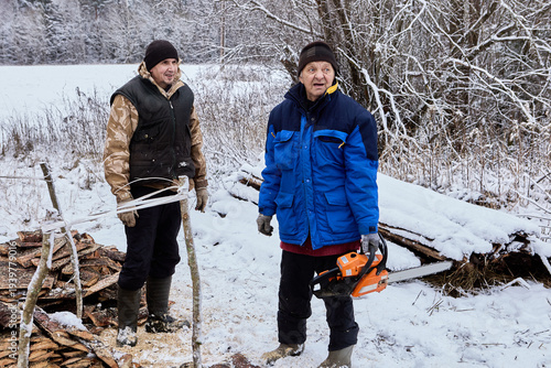 Fuel preparation for wood stoves farmers cut stacked slabwood into pieces using gasoline chainsaw.
