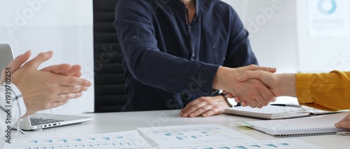 Businesspeople shaking hands, confirming partnership agreement while sitting in contemporary corporate sunny office. Business handshake concept