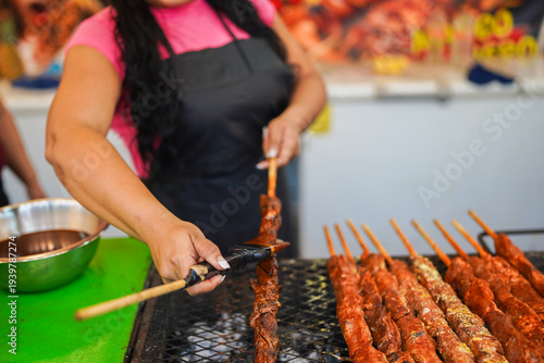 Latin woman entrepreneur grilling skewers at street food fair