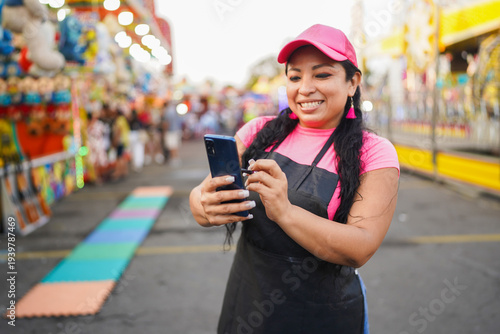 Latin woman entrepreneur using phone at fair