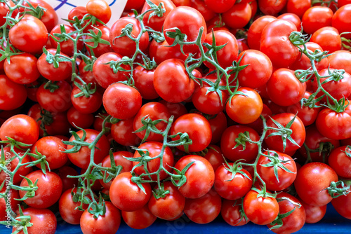  Fresh vibrant red vine tomatoes on a blue background at a local market