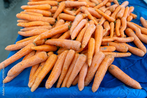 Fresh organic carrots on a blue cloth at a local farmer's market
